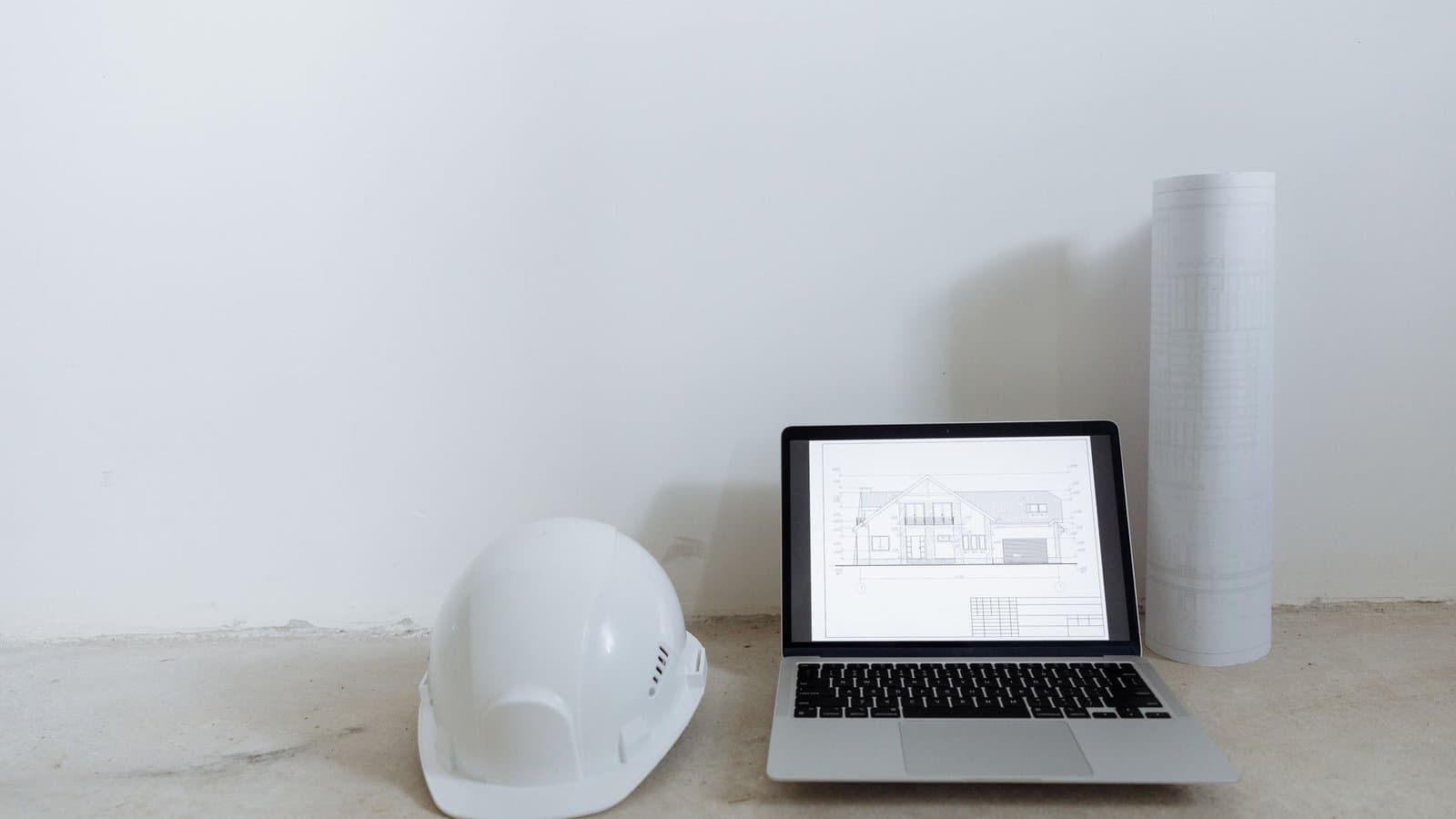 Ordinateur portable, casque et plans sur un poste de travail, usage d'un logiciel d'appel d'offre BTP