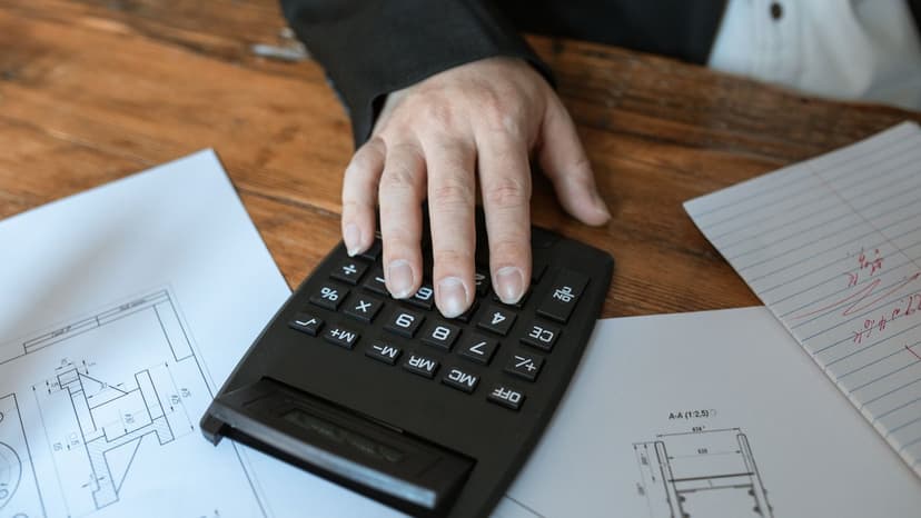 Calculatrice posée sur des plans techniques, chiffrage avant l'usage d'un logiciel de devis bâtiment